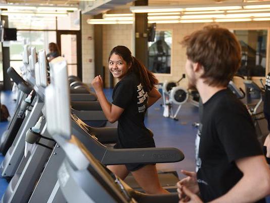 A pair of students are running on treadmills in the Gates Center fitness studio.